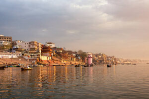 Ghats of Varanasi seen from the holy Ganges river at sunrise.